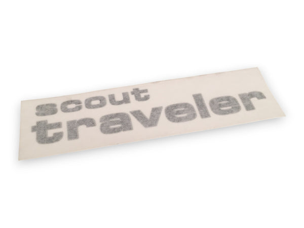 A rectangular beige sticker or decal with the words 'scout traveler' in gray textured lettering, shown at an angle on a white background.