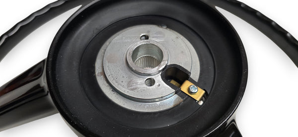 A black three-spoke steering wheel shown on a white background, with mounting hardware and a center cap placed below it.