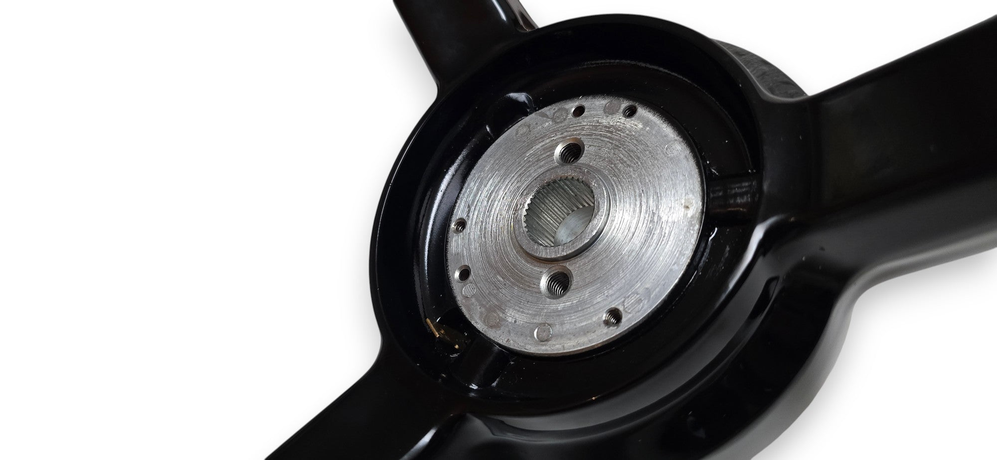 A black three-spoke steering wheel shown on a white background, with mounting hardware and a center cap placed below it.